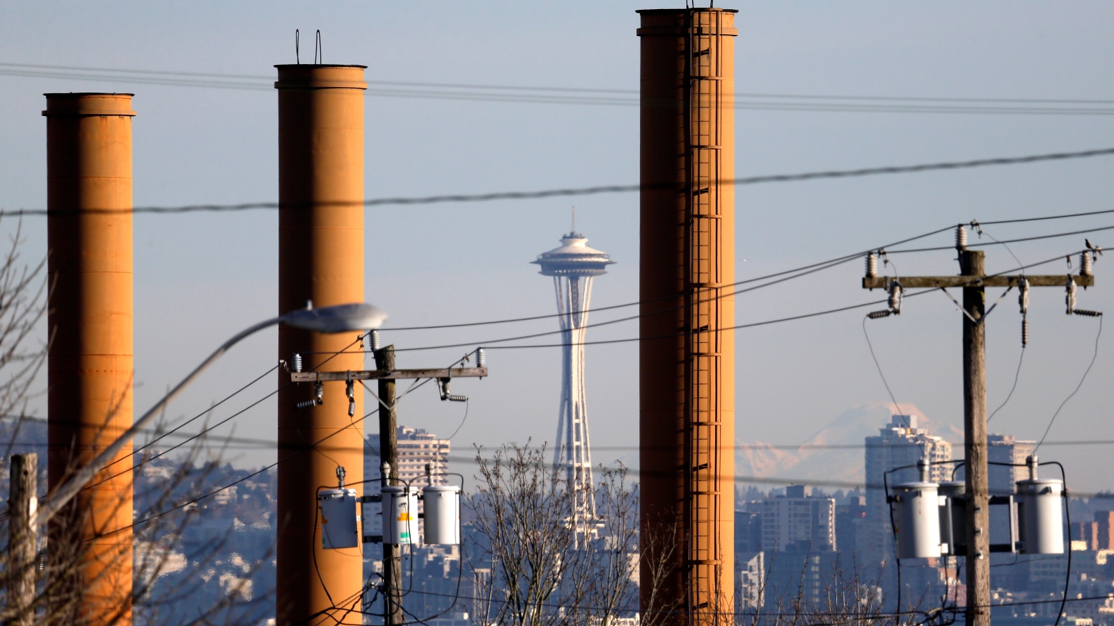 Photo of the Space Needle and downtown Seattle seen through industrial smokestacks.