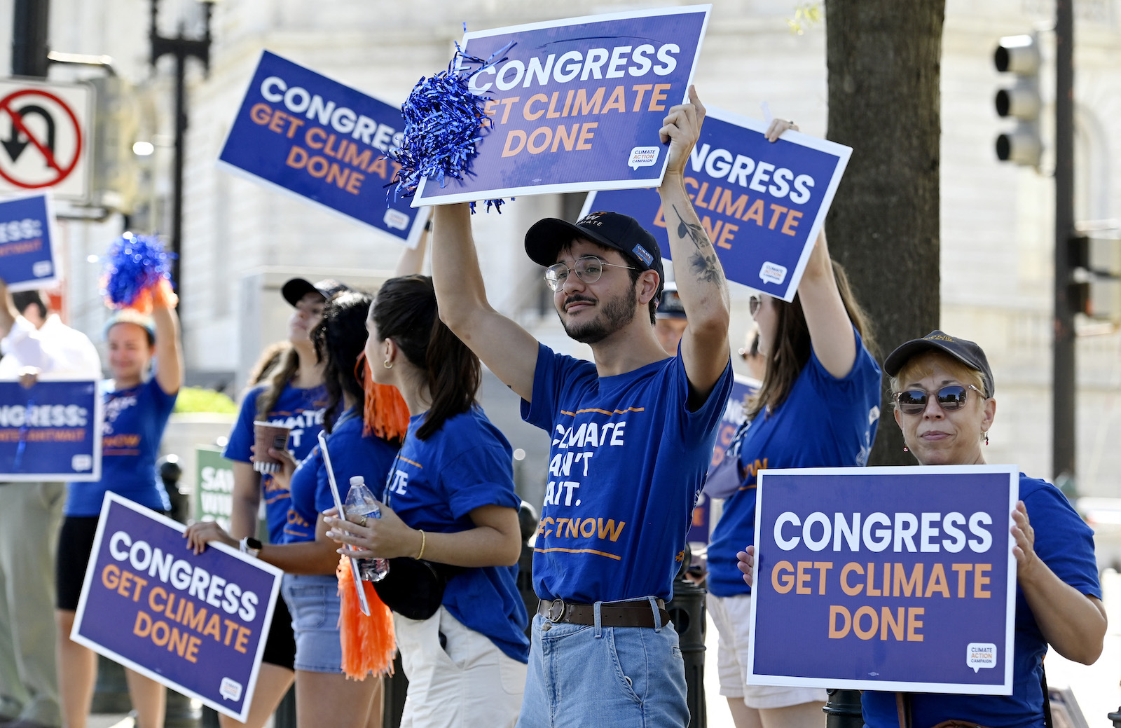 people hold signs that say get climate done